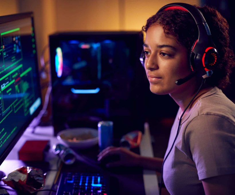 Female Teenage Hacker Sitting In Front Of Computer Screens Bypassing Cyber Security